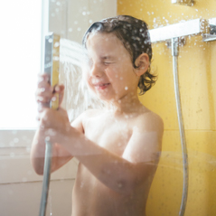 a boy spraying water on his face in shower