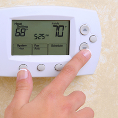 person pushing the thermostat temperature down